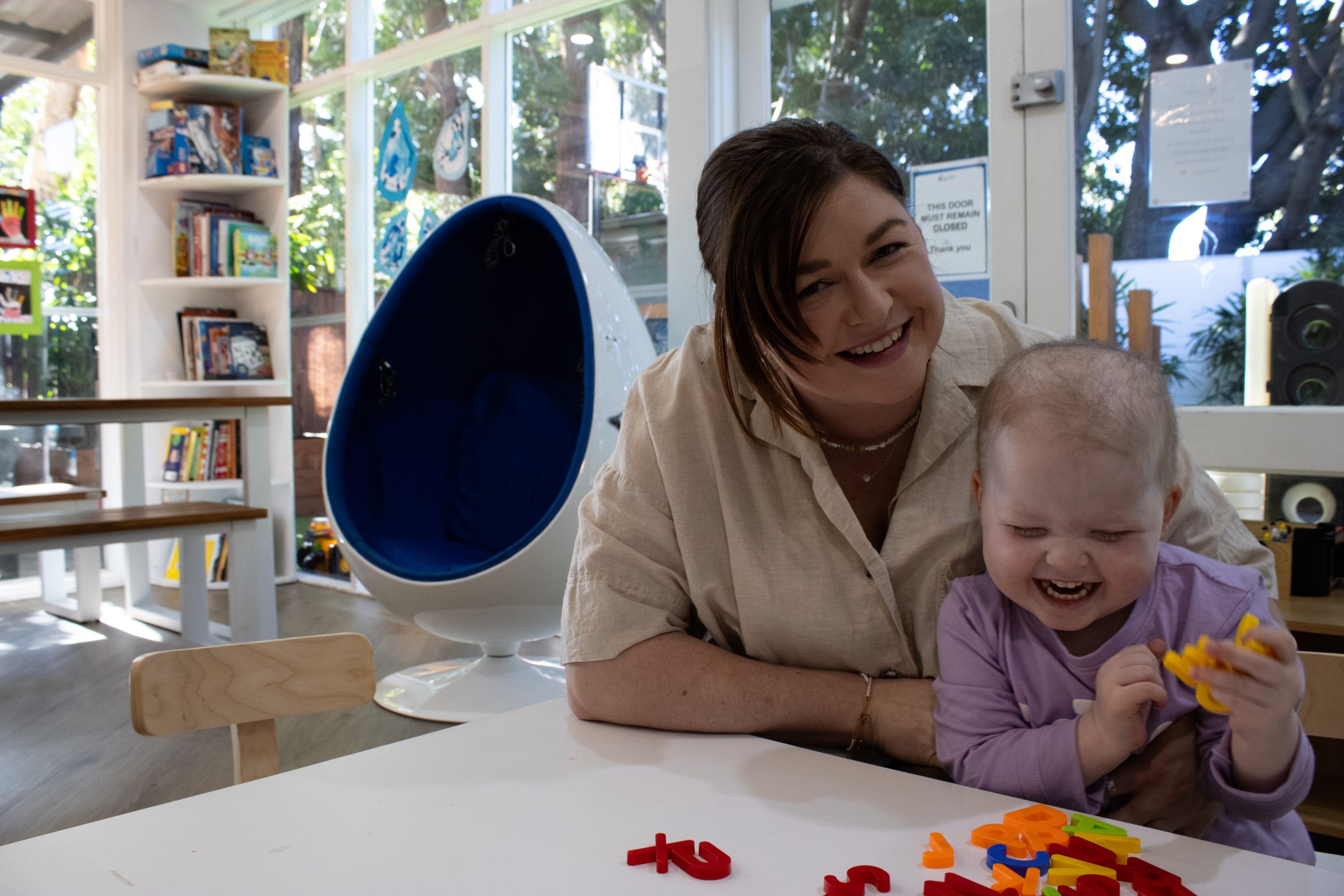 Courtney smiles beside Georgie as they play together during their stay at Ronald McDonald House Sydney.