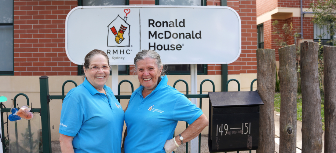 Volunteers Marg and Jill standing in front of the Ronald McDonald House Sydney sign.